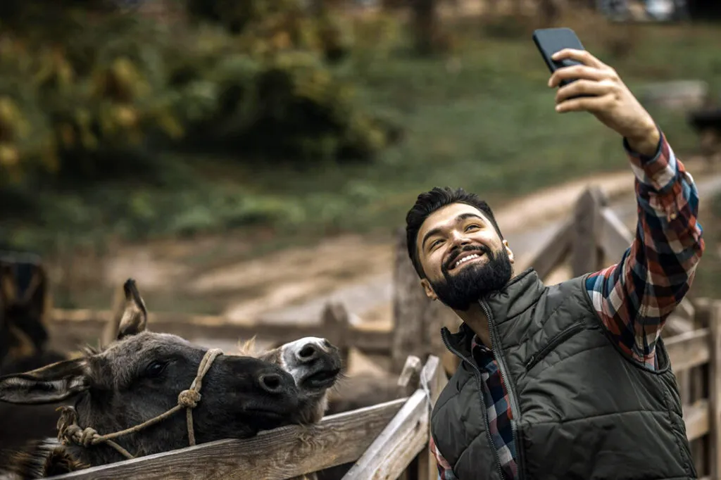 A man taking a selfie with a donkey.